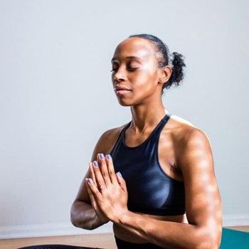 Woman eyes closed hands together meditating