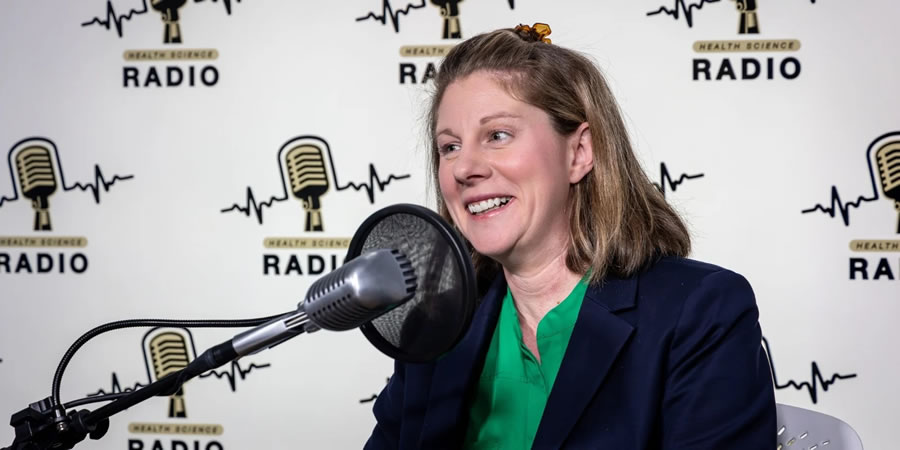 Dr. Amanda Piquet  speaking into a microphone for a podcast