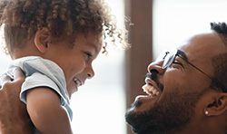 Man holding up baby both smiling