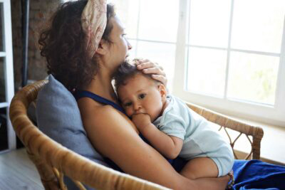Woman holding a baby looking out of window