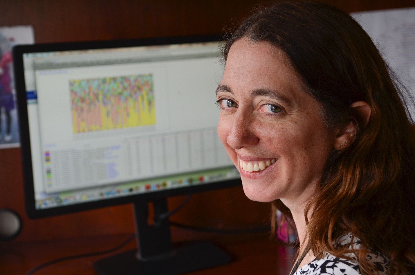 Cathy Lozupone sitting at computer with graph and data on the screen