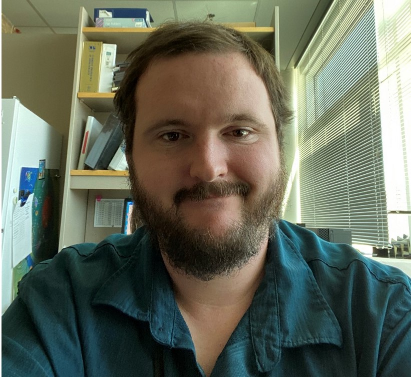 Cameron Lloyd smiling, wearing a blue button up shirt