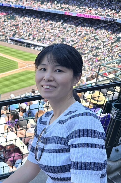 Chiharu Yamauchi smiling at a baseball game, seated in the stands