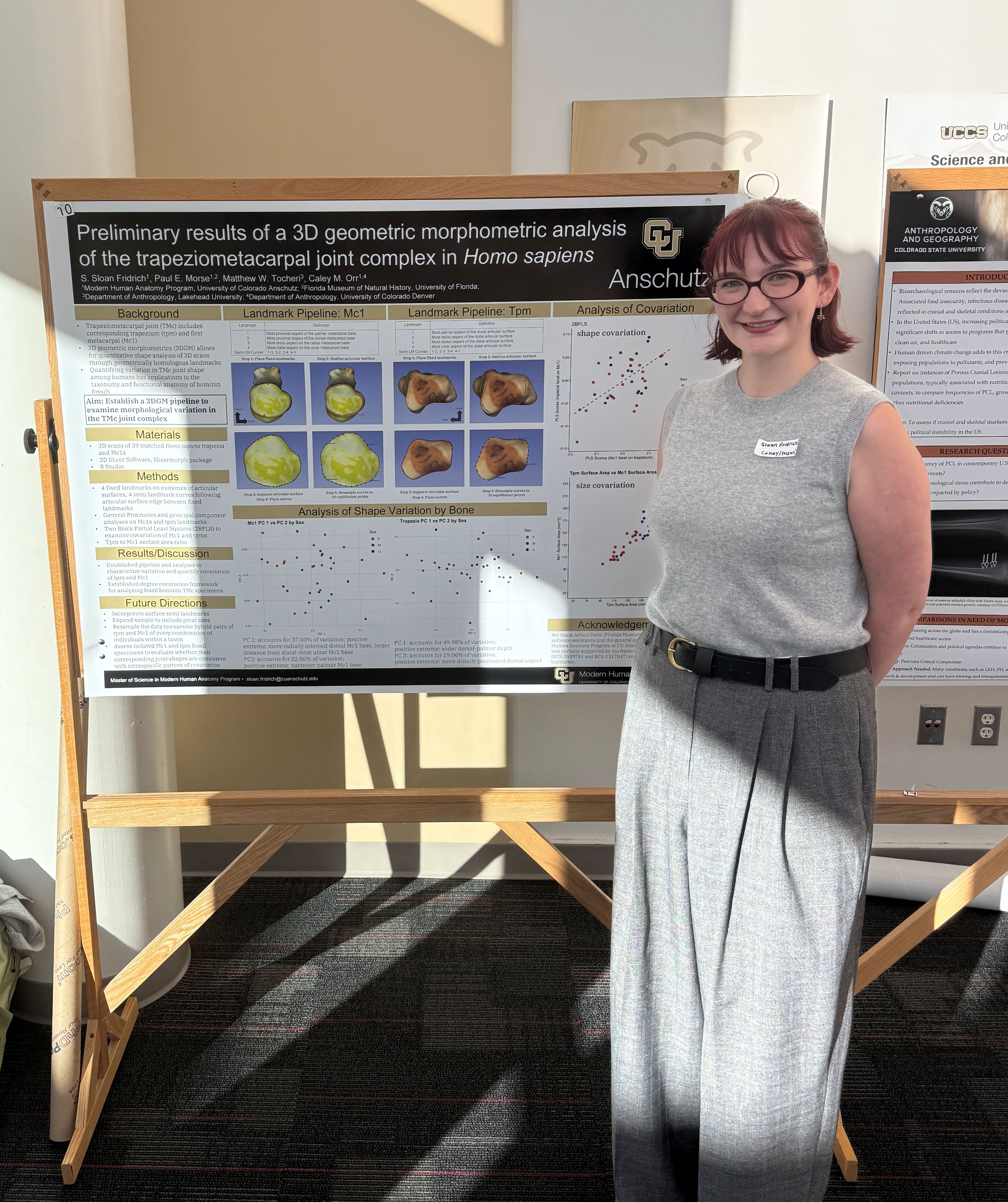 Student, Sloan Fridrich, standing beside research poster