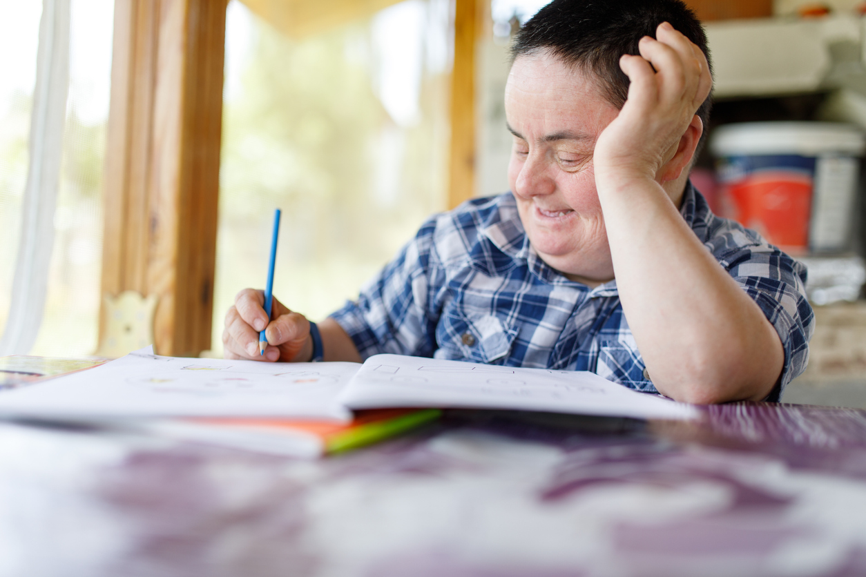 Woman with Down Syndrome drawing in a workbook