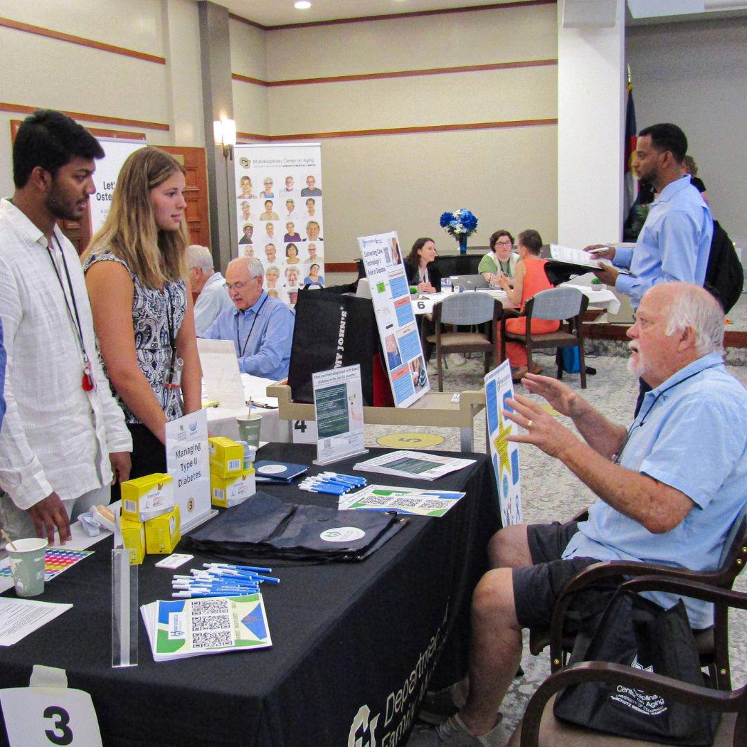 Older adult community member talking with research students at the Shalom Park Research Roadshow.