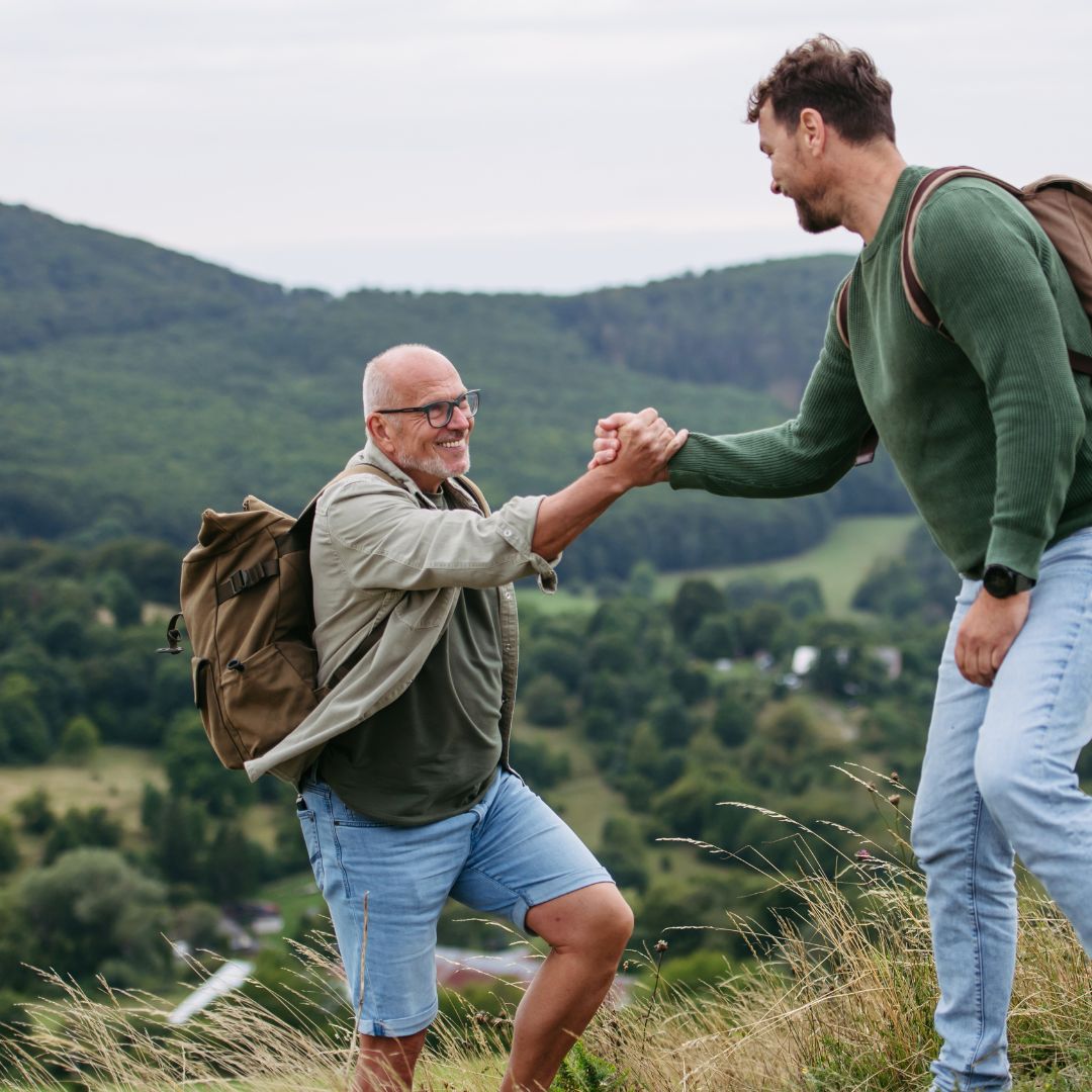 Older adult man on a hike with his son.