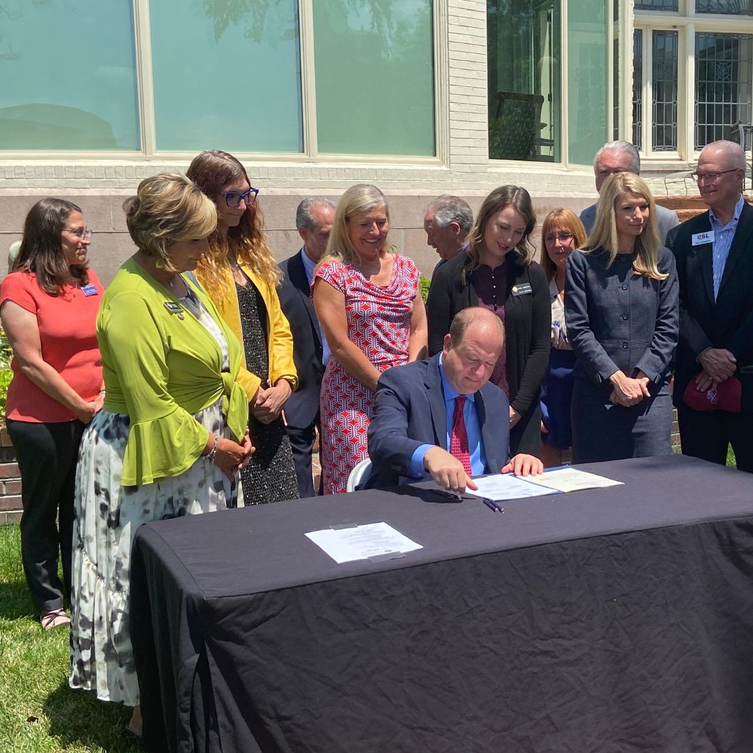 Members of the MCoA watch as Governor Polis signs an aging bill.