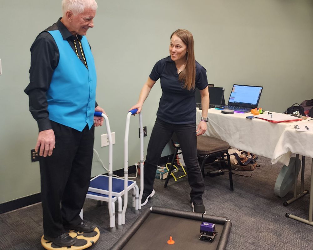 Older adult and CU Anschutz researcher conducting research by testing out a new balance board.