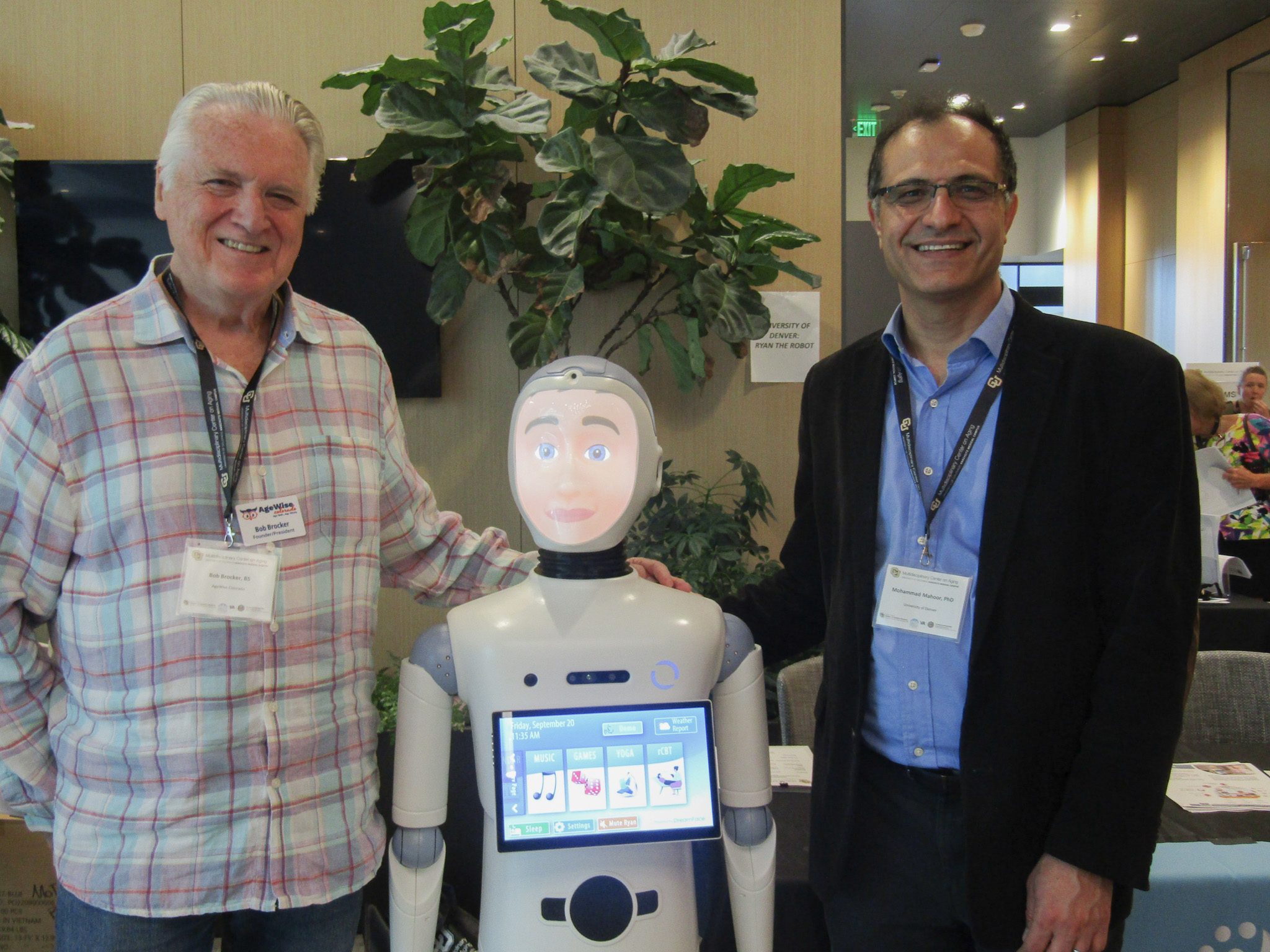 A participant and researcher pose next to Ryan the Robot.