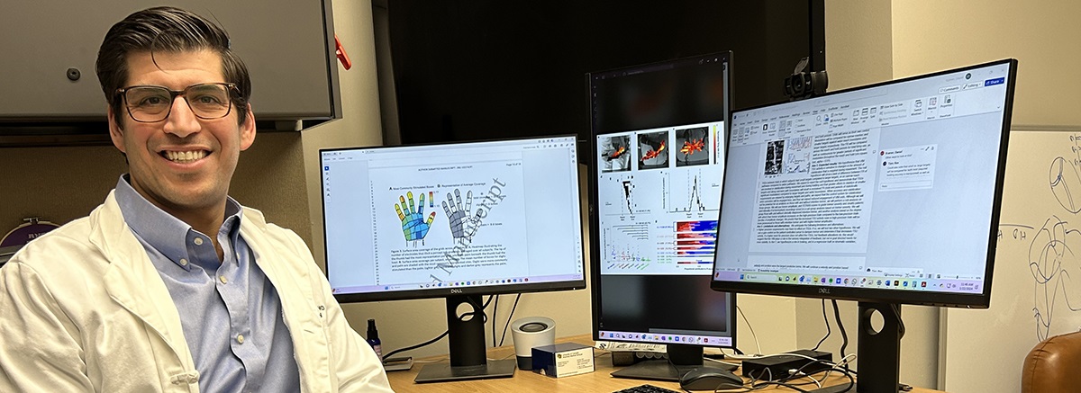 DanielKramerMDsittingatdeskwiththreemonitors