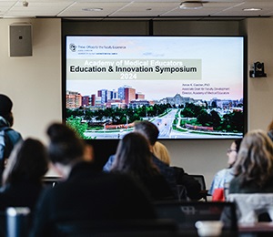 studentsfacultywatchingsymposiumpresentationinclassroom