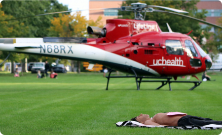 man lying in grass near helicopter pretending to be dead or injured