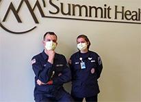 Twouchworkerswearingmasksunderhospitalsign