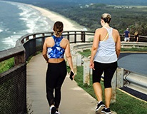 Womeninworkoutgearwalkingnearoceanseenfromback