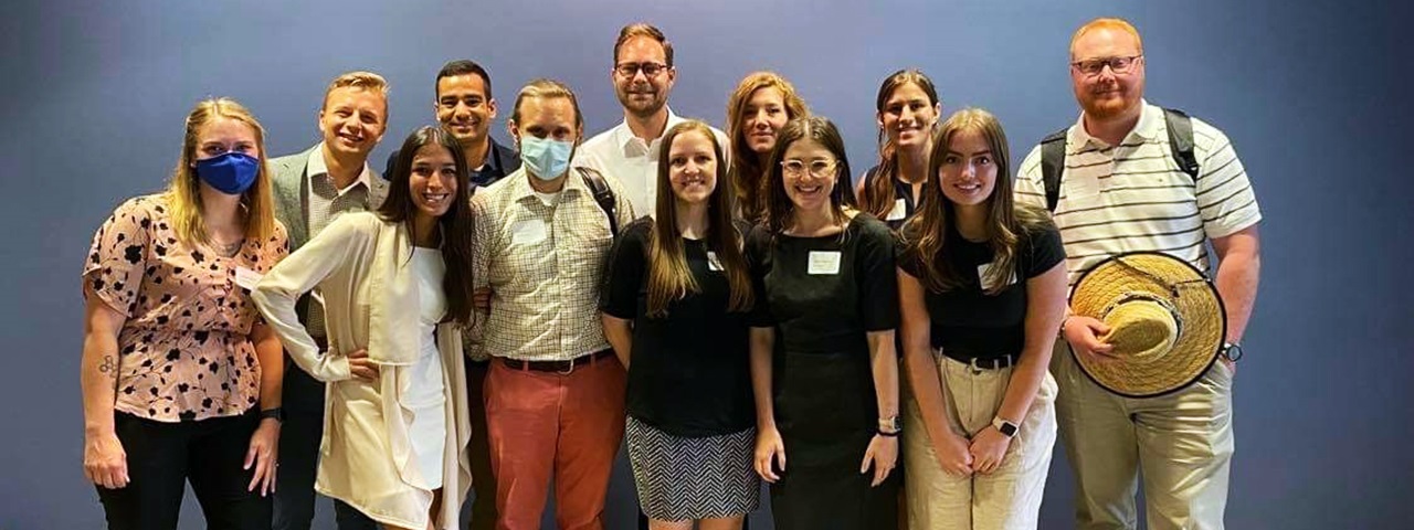 fcbclassof2025TwelvestudentsstandingtogetherinfrontofbluewallTwomasked