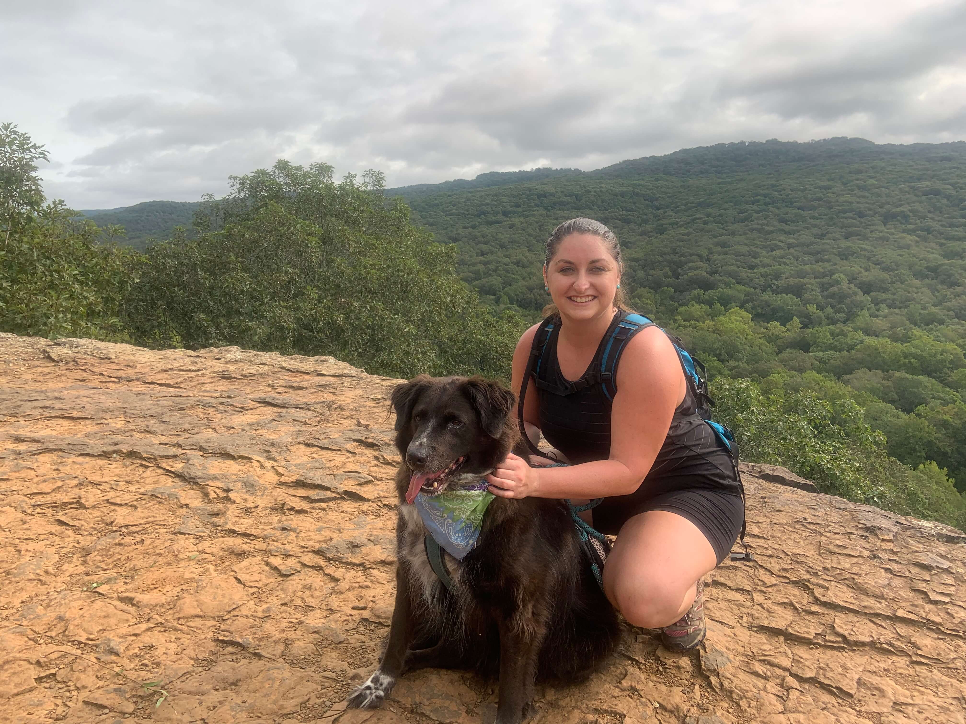Mara D.  with black and white dog with wilderness vista behind her
