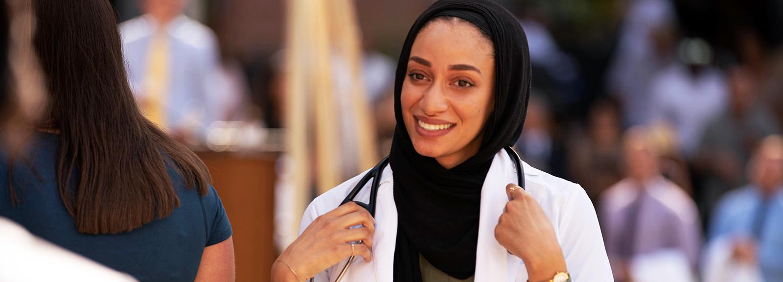 matriculantwearingnewwhitecoatandstethoscopewalkingacrossstage