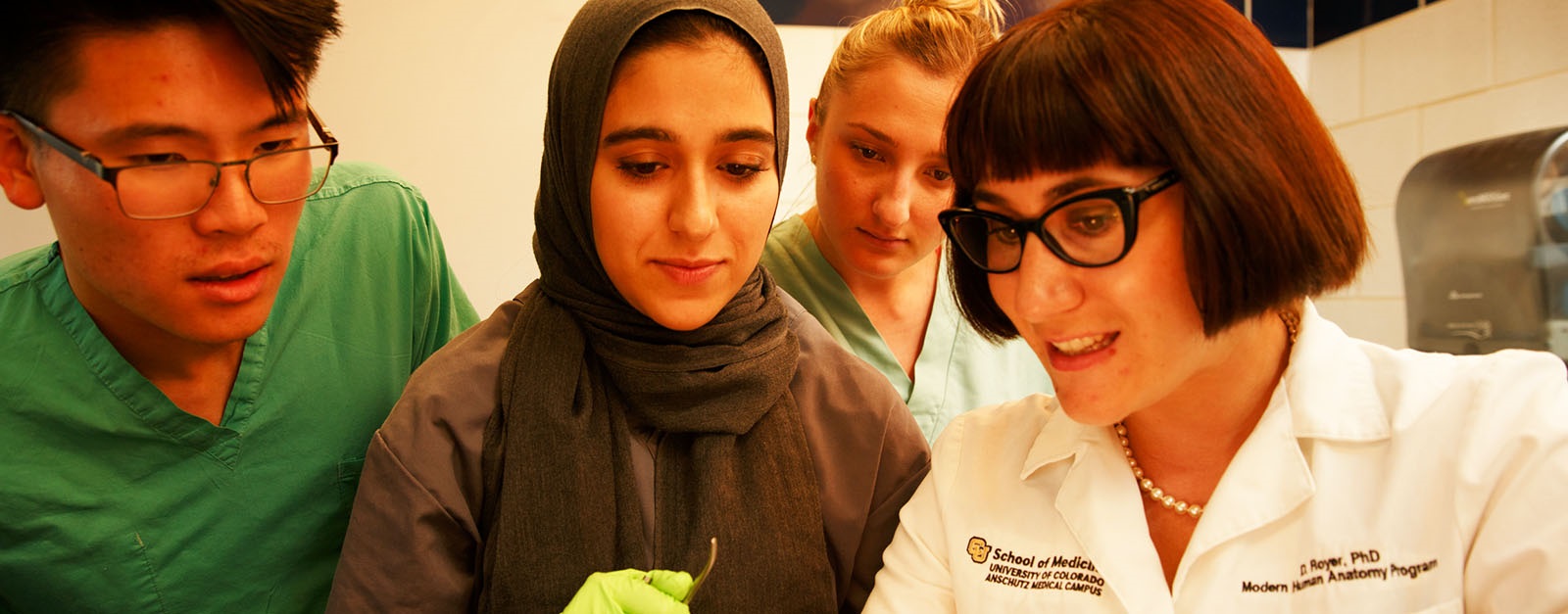 Threemedicalstudentswithinstructorinanatomylabstandingovertable