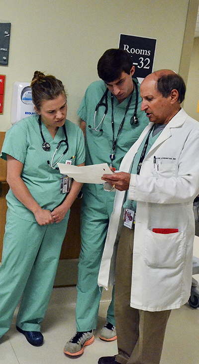 steve lowenstein instructing two students in scrubs