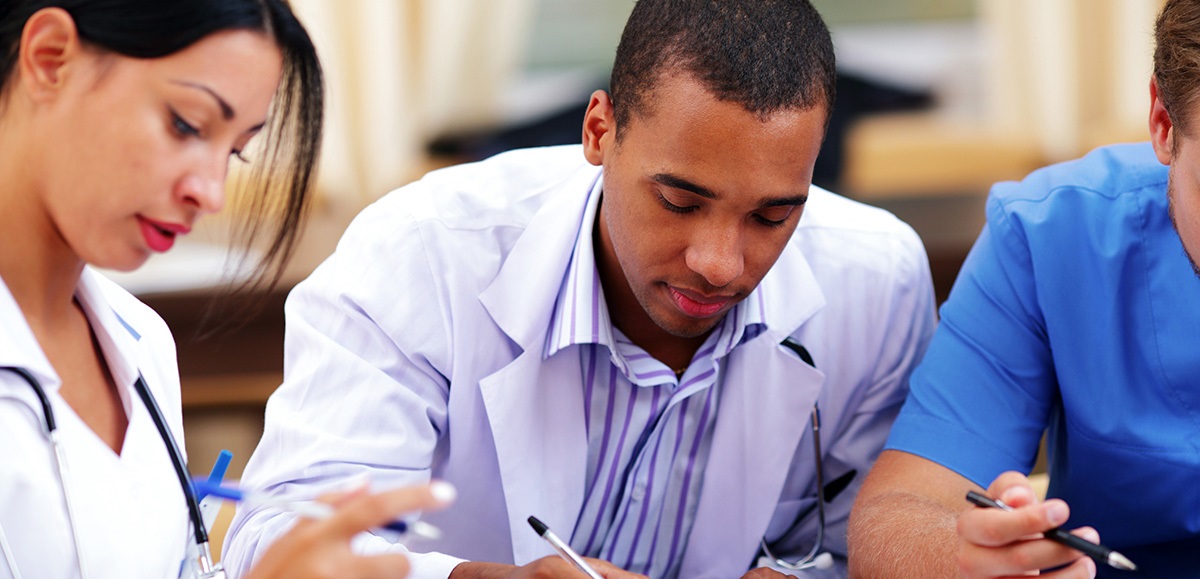ThreeStudentsstudyingandwritingTwoinwhitecoatsoneinbluescrubs