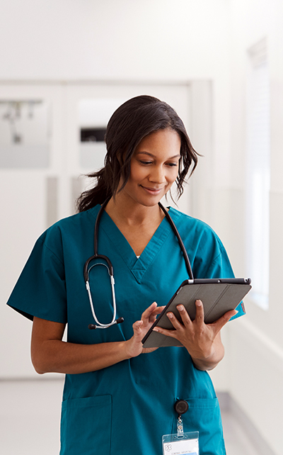 Womaninscrubsstandinginwhitehallwaywithclipboard