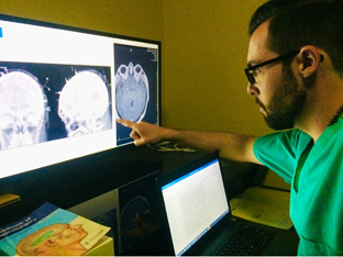 Student in scrubs  pointing at xray image.