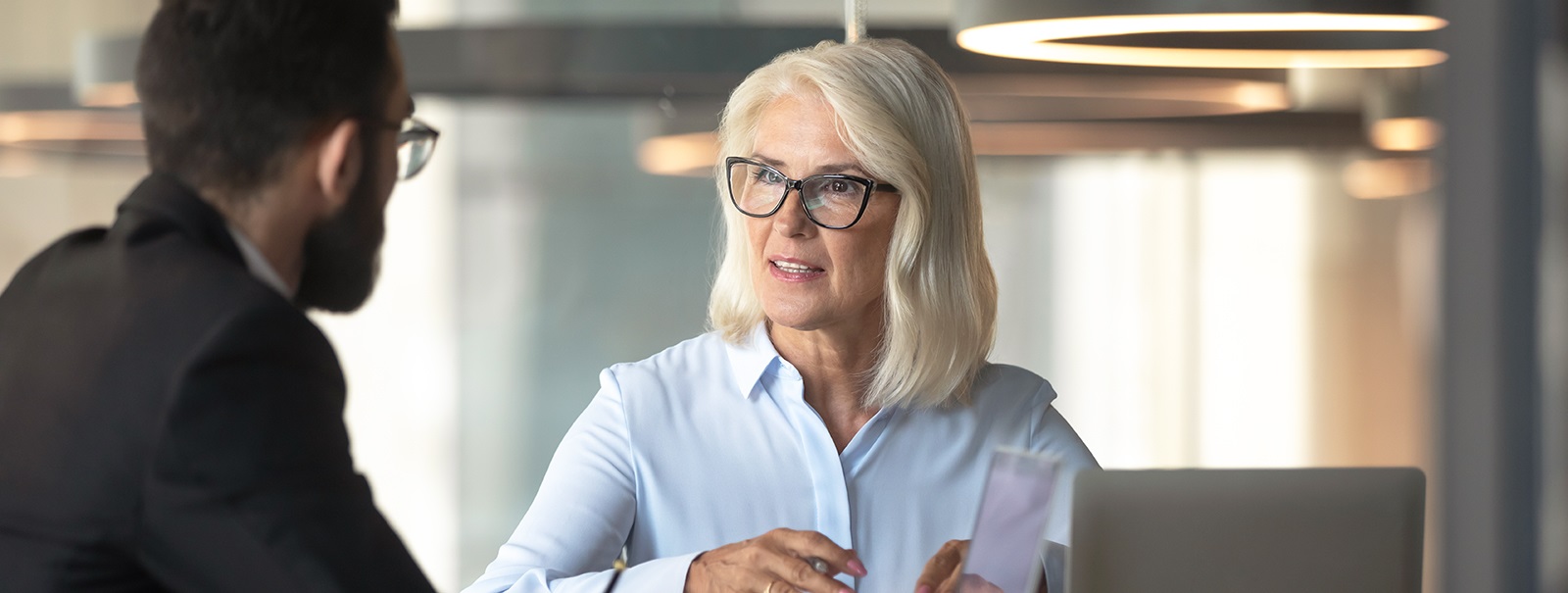 WomaninwhiteinterviewingmanseeninprofileBackgroundblurred