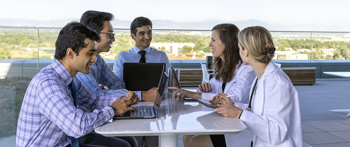 severalstudentsandfacultygatheredaroundatableonterrace