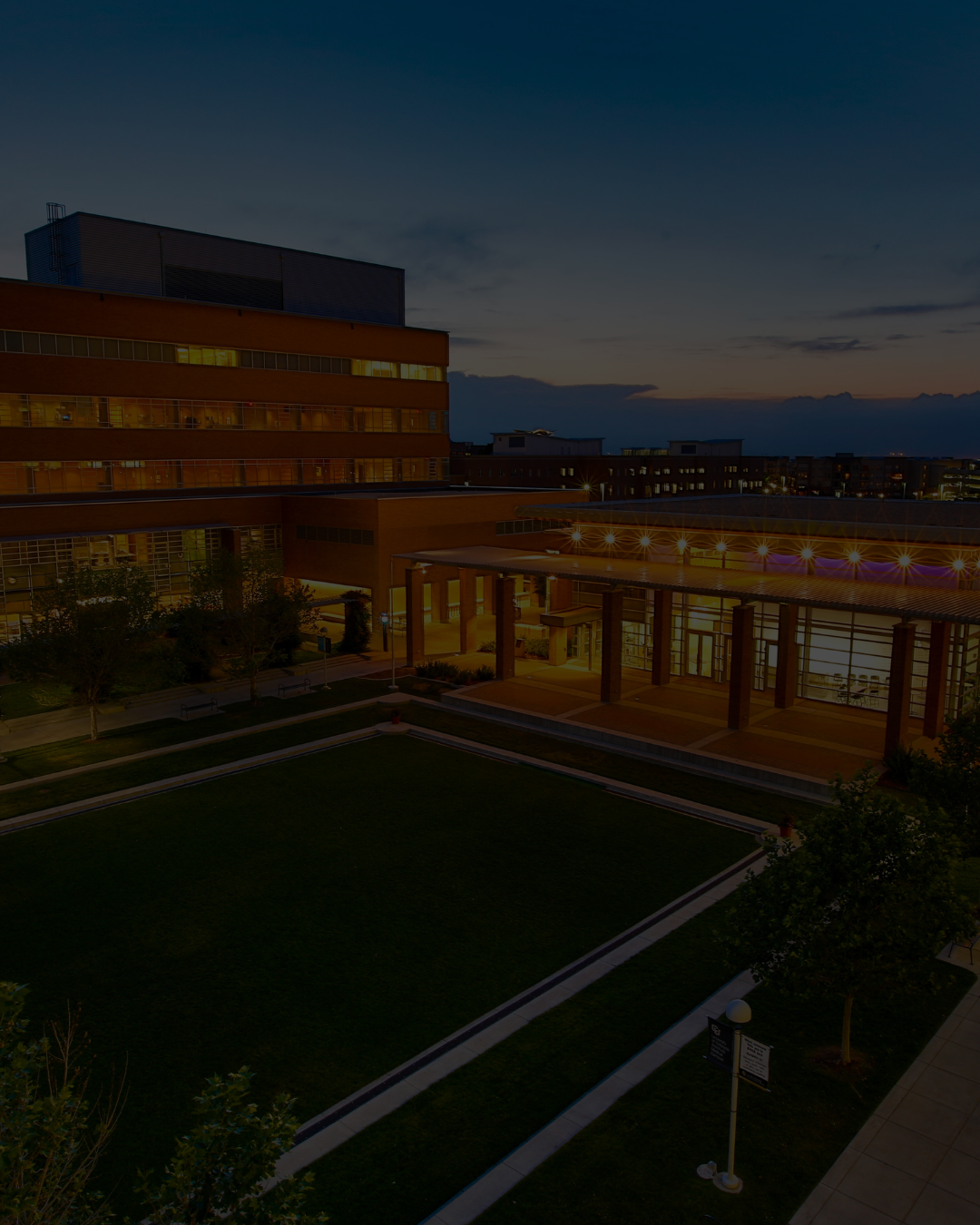 Buildingglowingineveninglightsetbehinduniversityquad