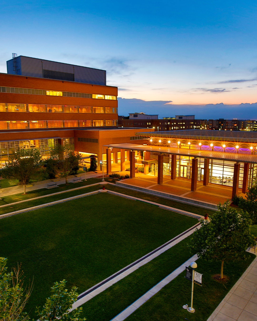 Abuildingglowswithorangelightintheeveningontheuniversityquad
