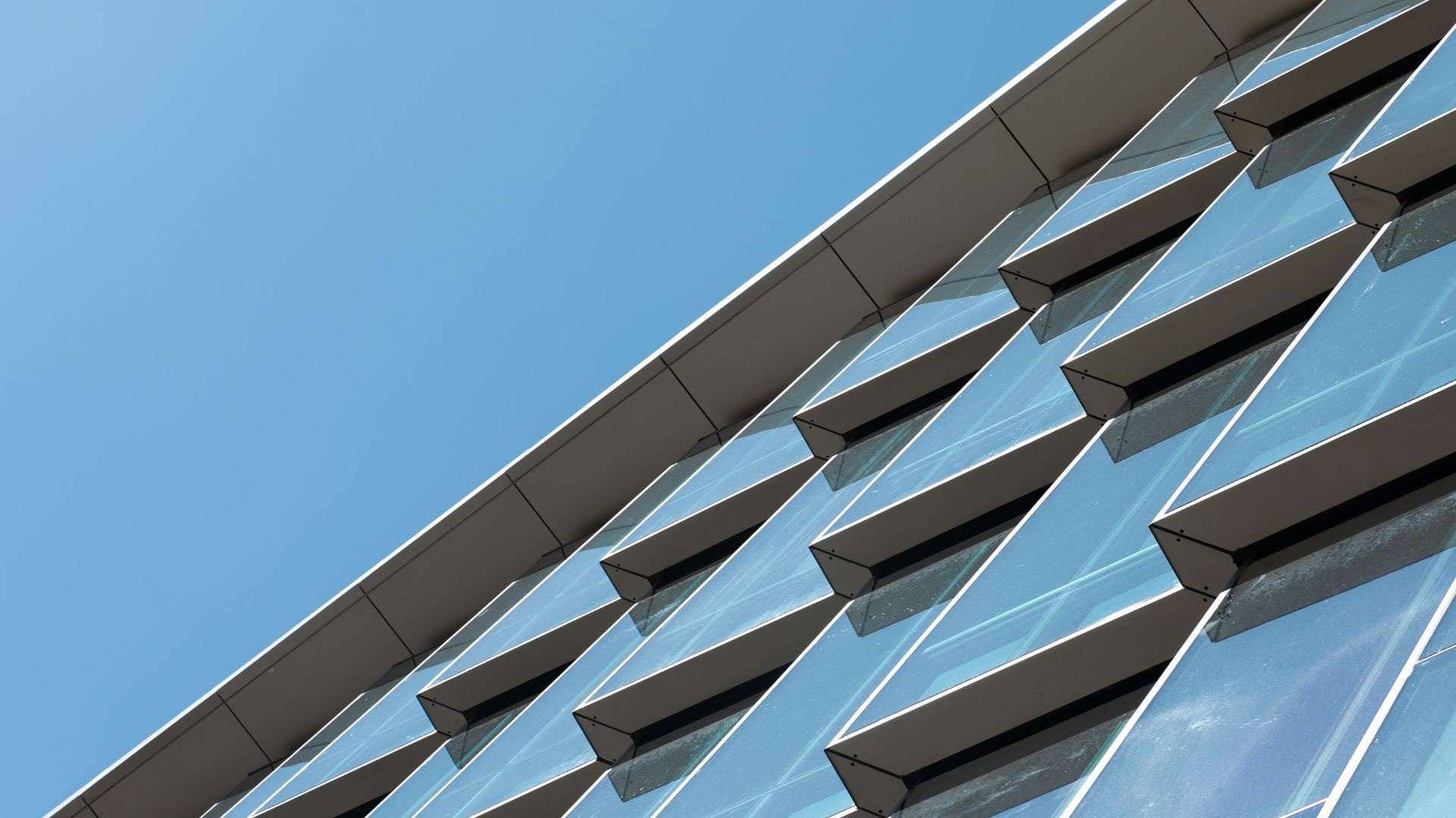 Buildingfacademadeofmanyglasstrianglesonablueskybackground