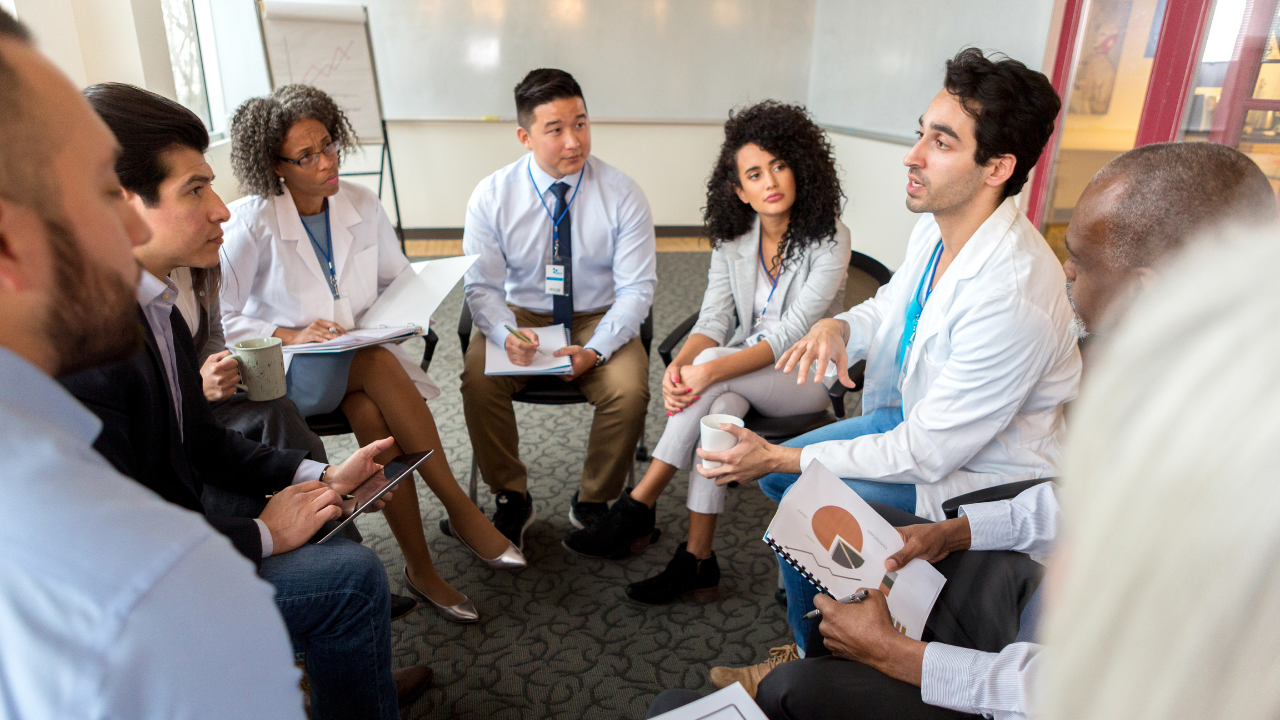 groupofdoctorsinwhitecoatssitinacircleforameeting