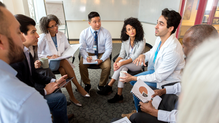 groupofdoctorsinwhitecoatssitinacircleforameeting
