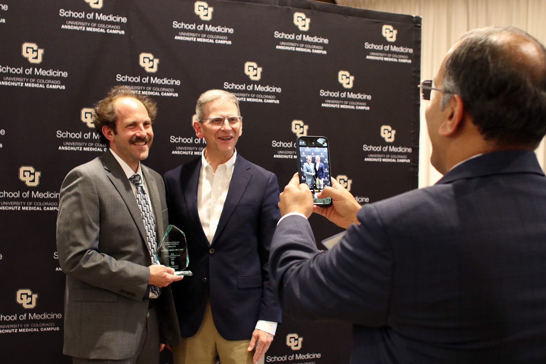 twopeoplesmilingandonepersontakingthepicturewithaphone