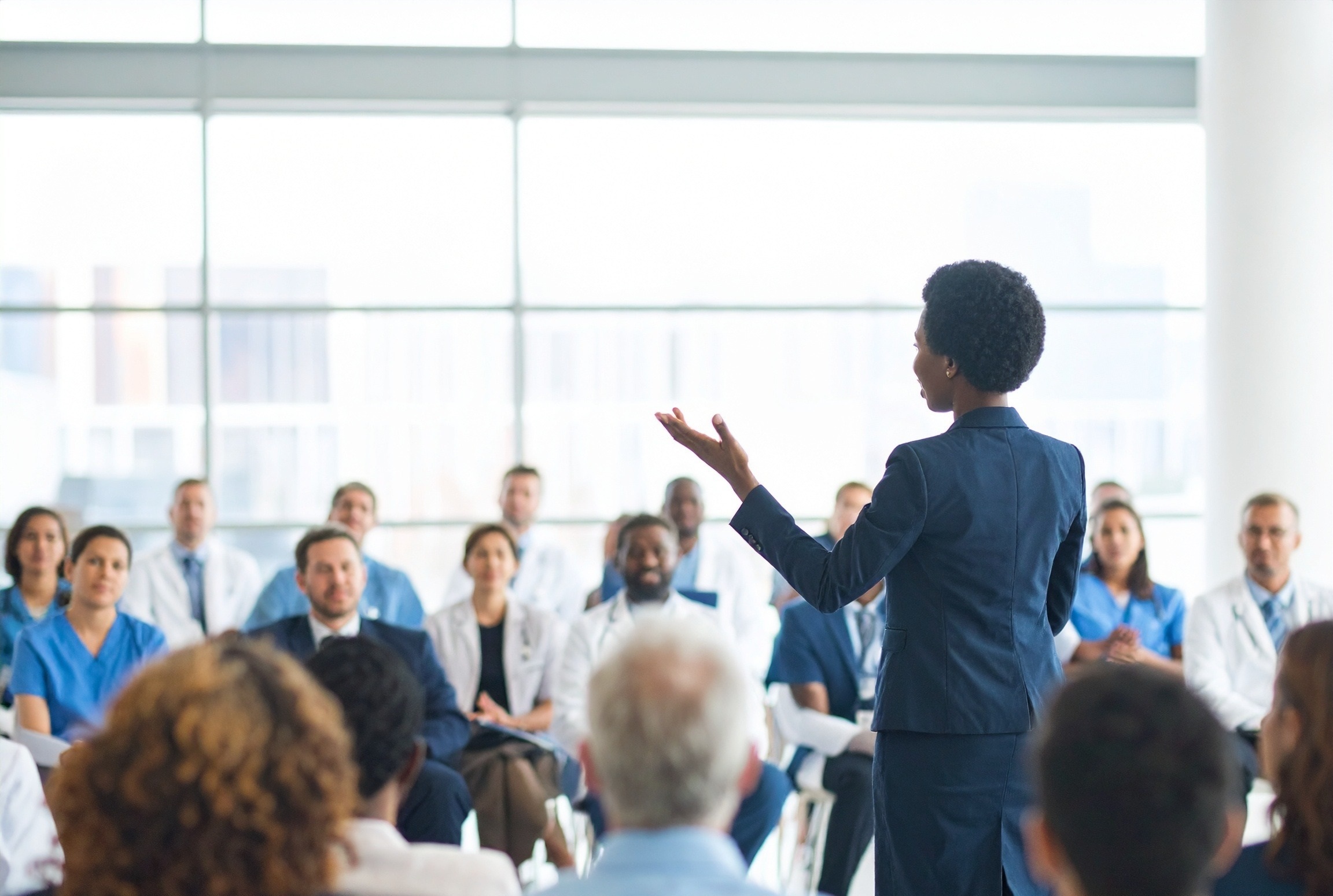 Professionalwomandeliveringapresentationtoagroupofhealthcareprofessionalsatamedicaleducationevent