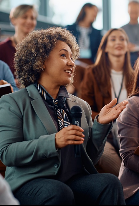 Membersinanaudiencewithonememberholdingmicrophoneandspeaking