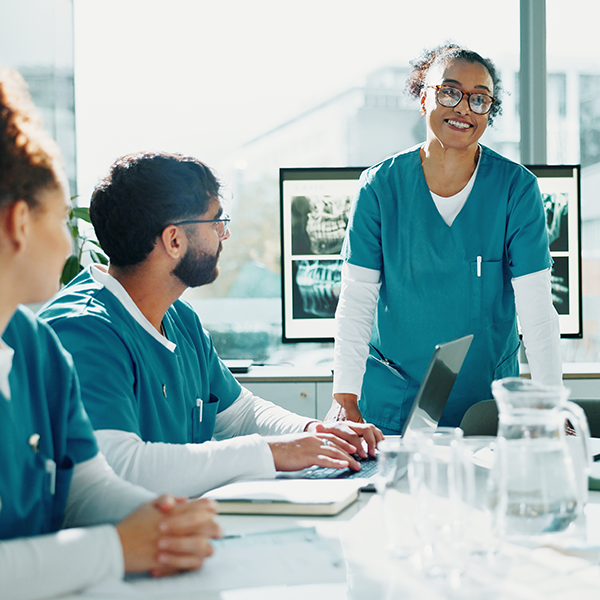 Practitioner in scrubs speaking to others in scrubs