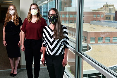 Threestudentswearingmasksstandinginhospitalbywindow