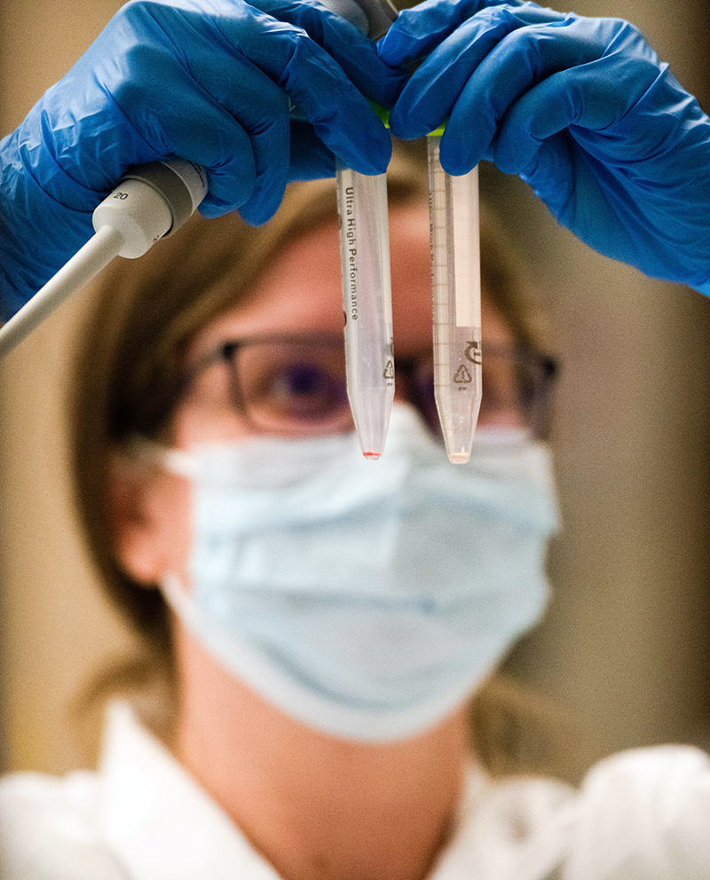 maskedresearcherlookingupattwovialsshesholding