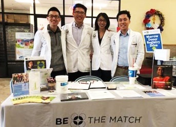 groupoffourstandingbehindatable