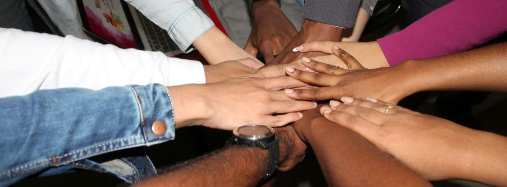 A diverse group of hands stacked together in a show of unity and teamwork, symbolizing collaboration and support.