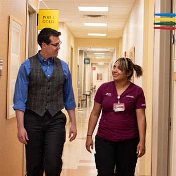 Family Medicine resident and medical assistant walking down a clinic hallway.