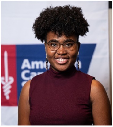 Woman with glasses and a afro in a sleeveless maroon tank