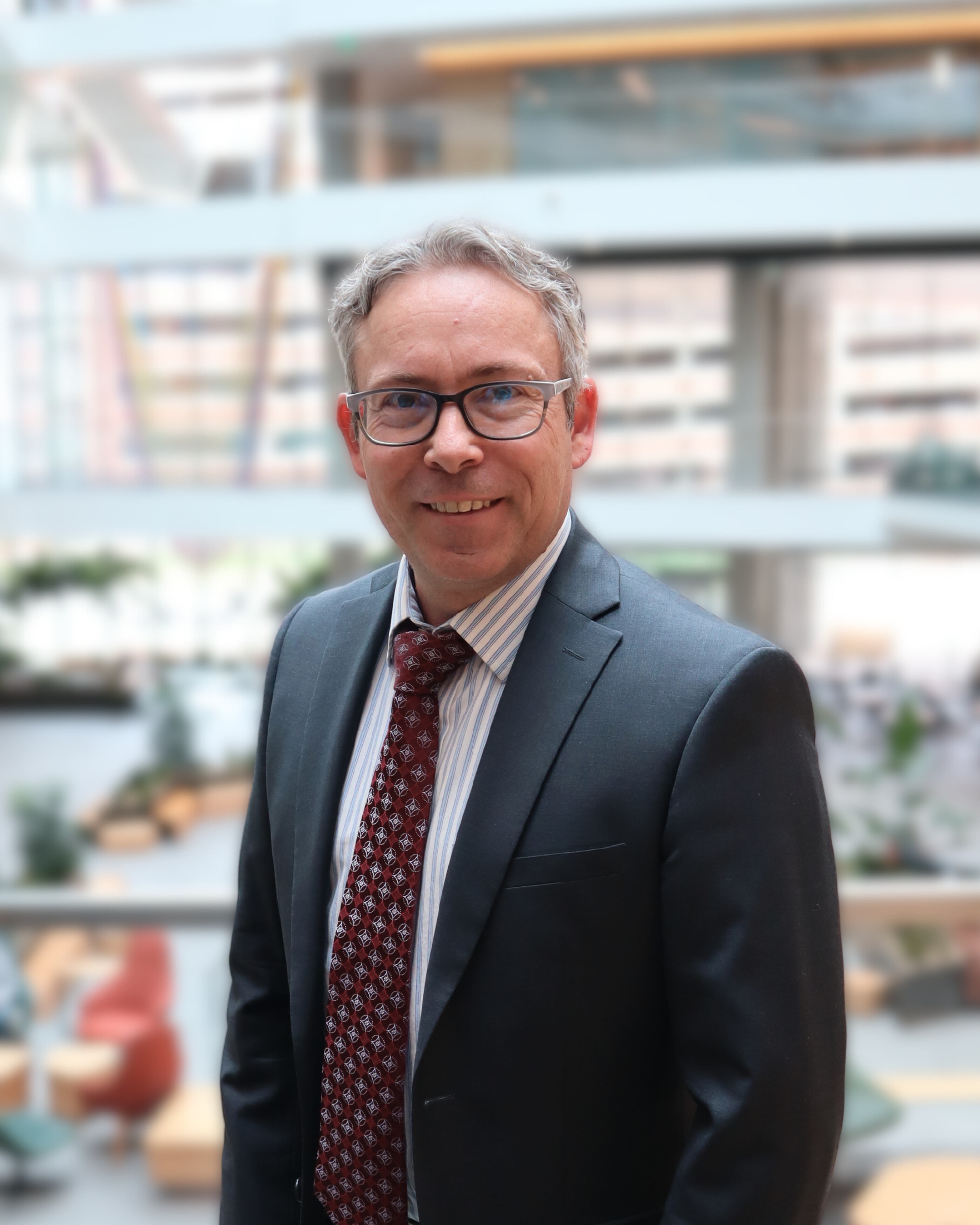 Grey haired man in glasses and a red tie