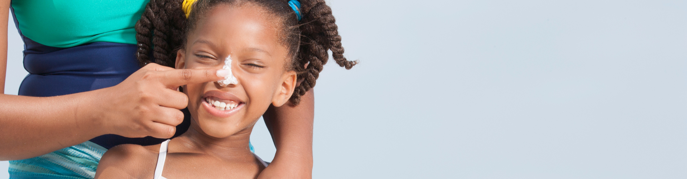 adult putting sunscreen on young girl's nose