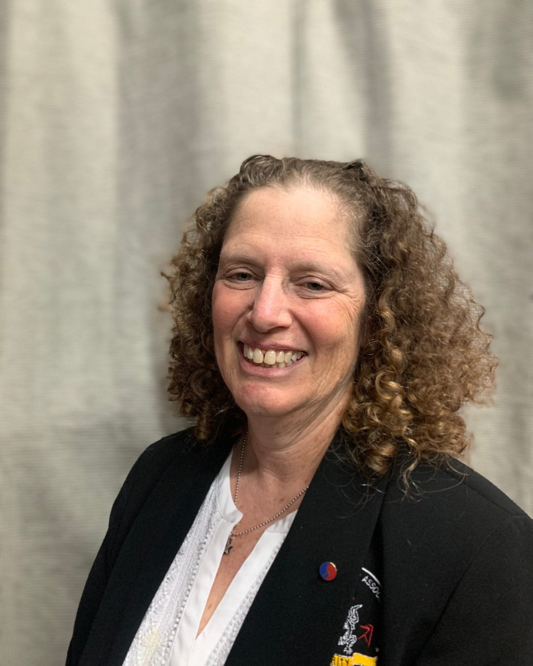 Woman with curly hair in a white shirt and blue blazer