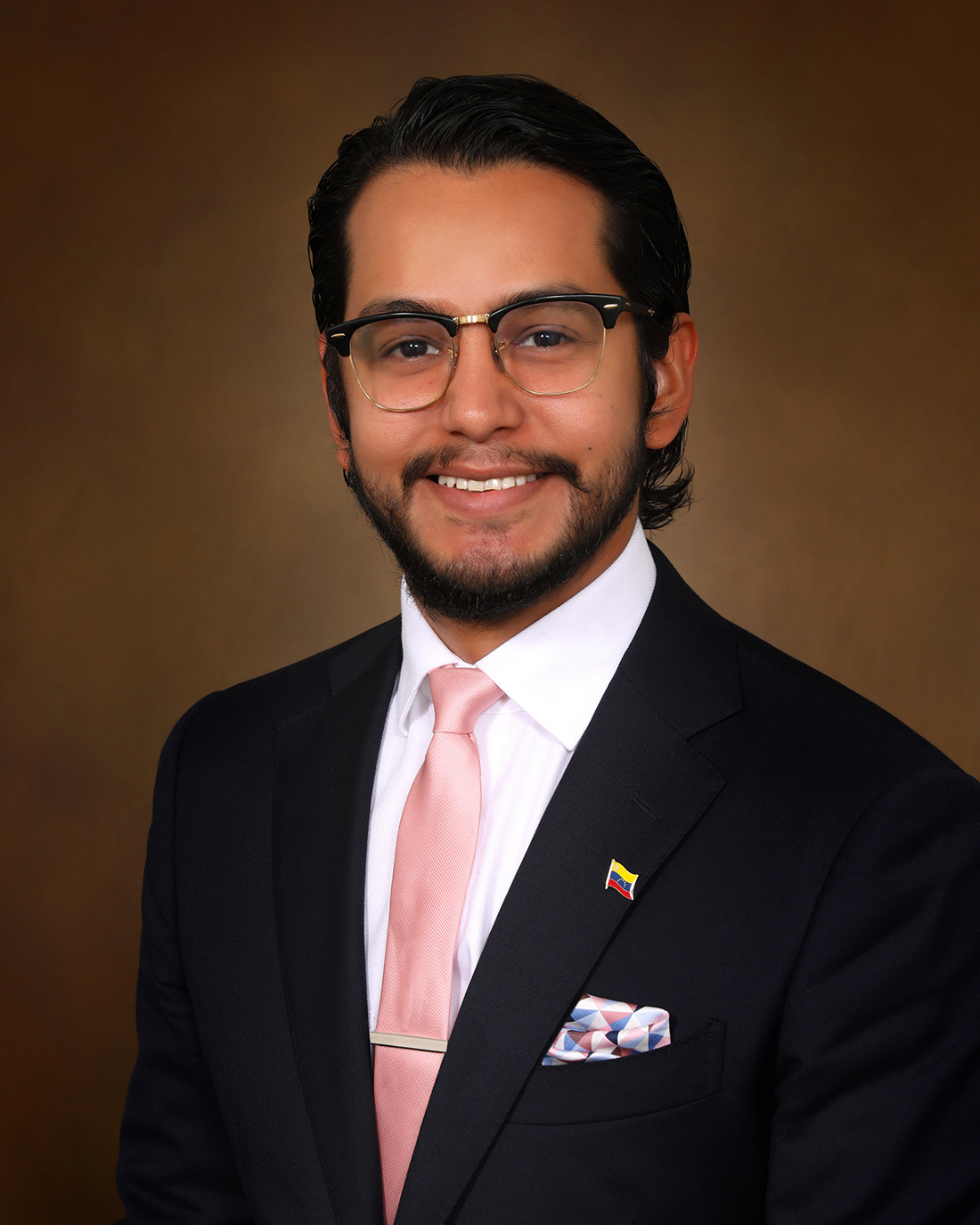 Man in a dark suit with a pink tie