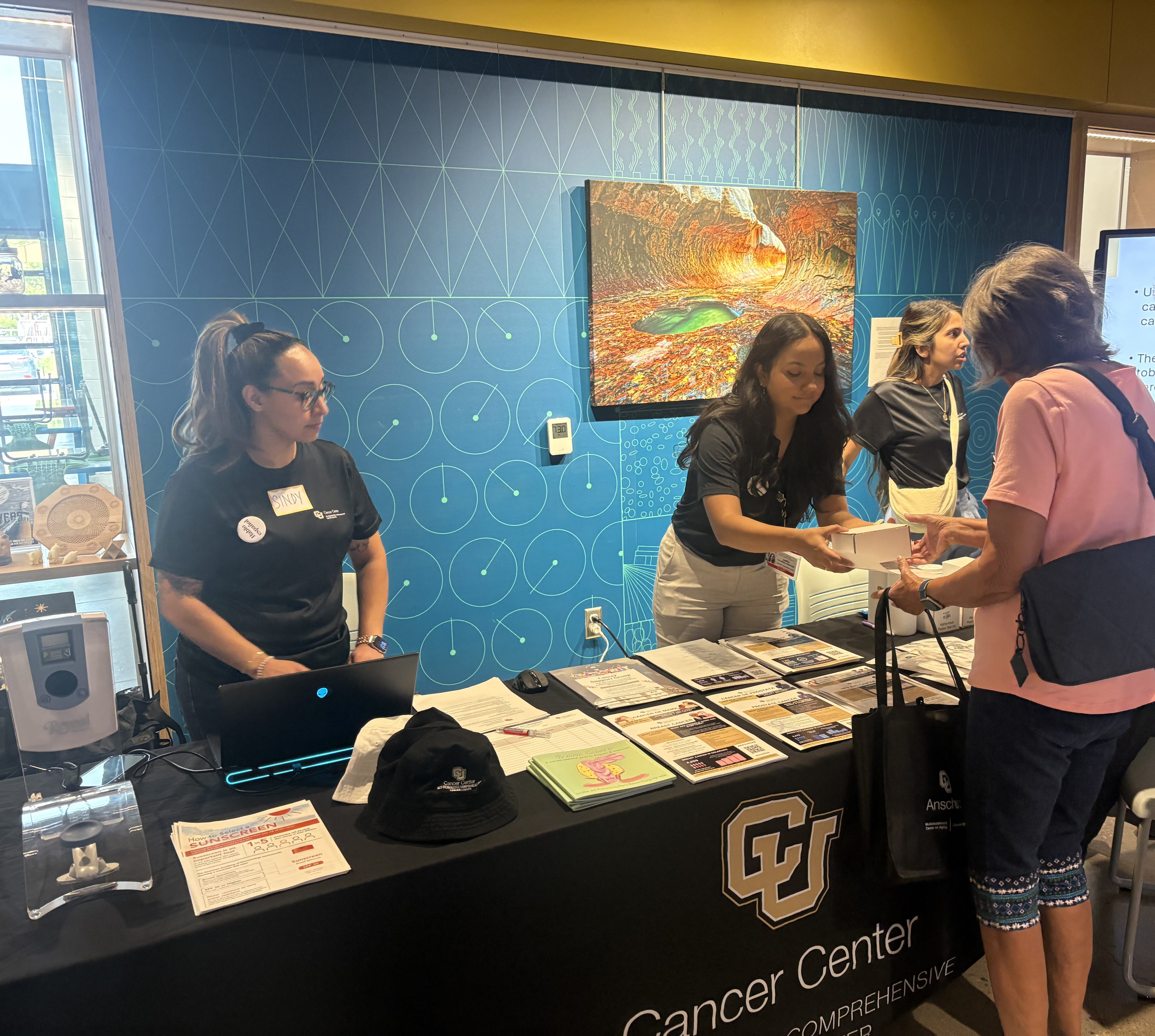three women working a cancer center table
