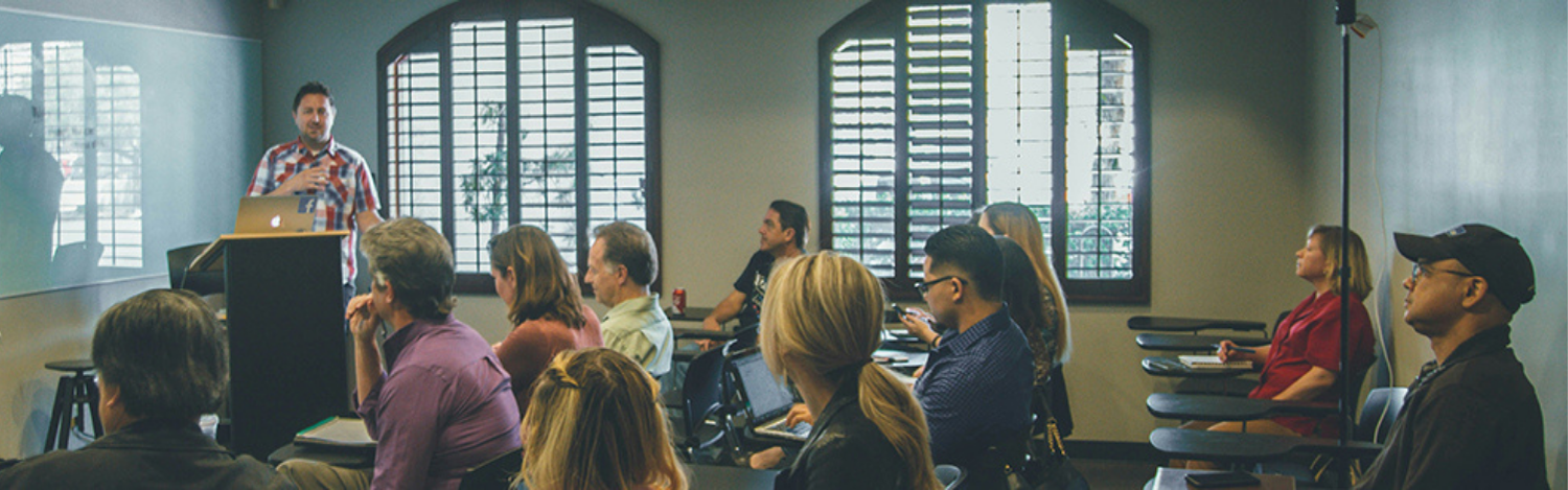 group of people listening to a peaker at a podium